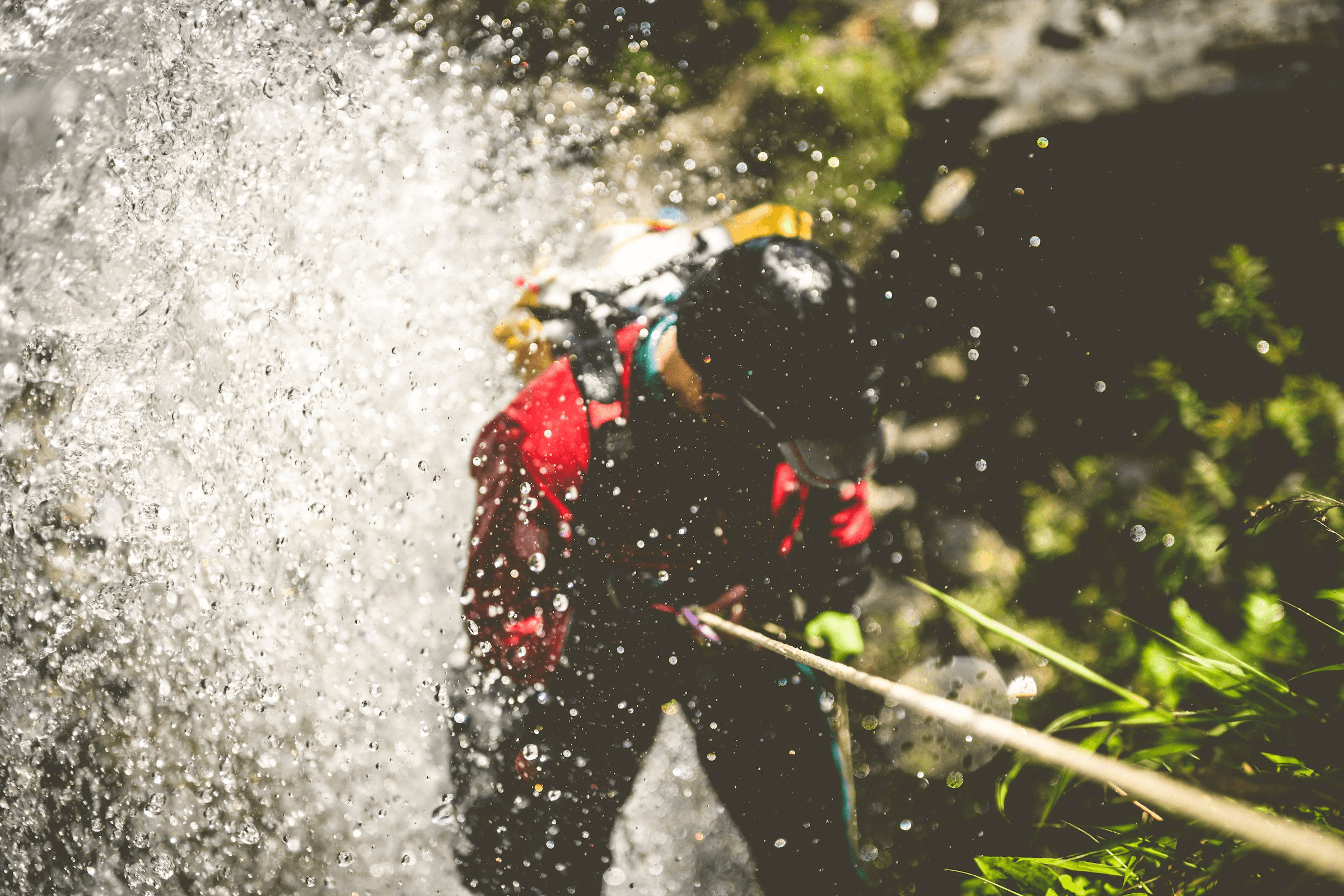 Eine Person seilt sich beim Canyoning durch einen Wasserfall ab