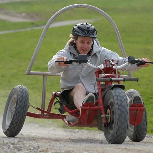 Ein Mann fährt auf einem Bullcart einen Hügel in Lenggries hinab