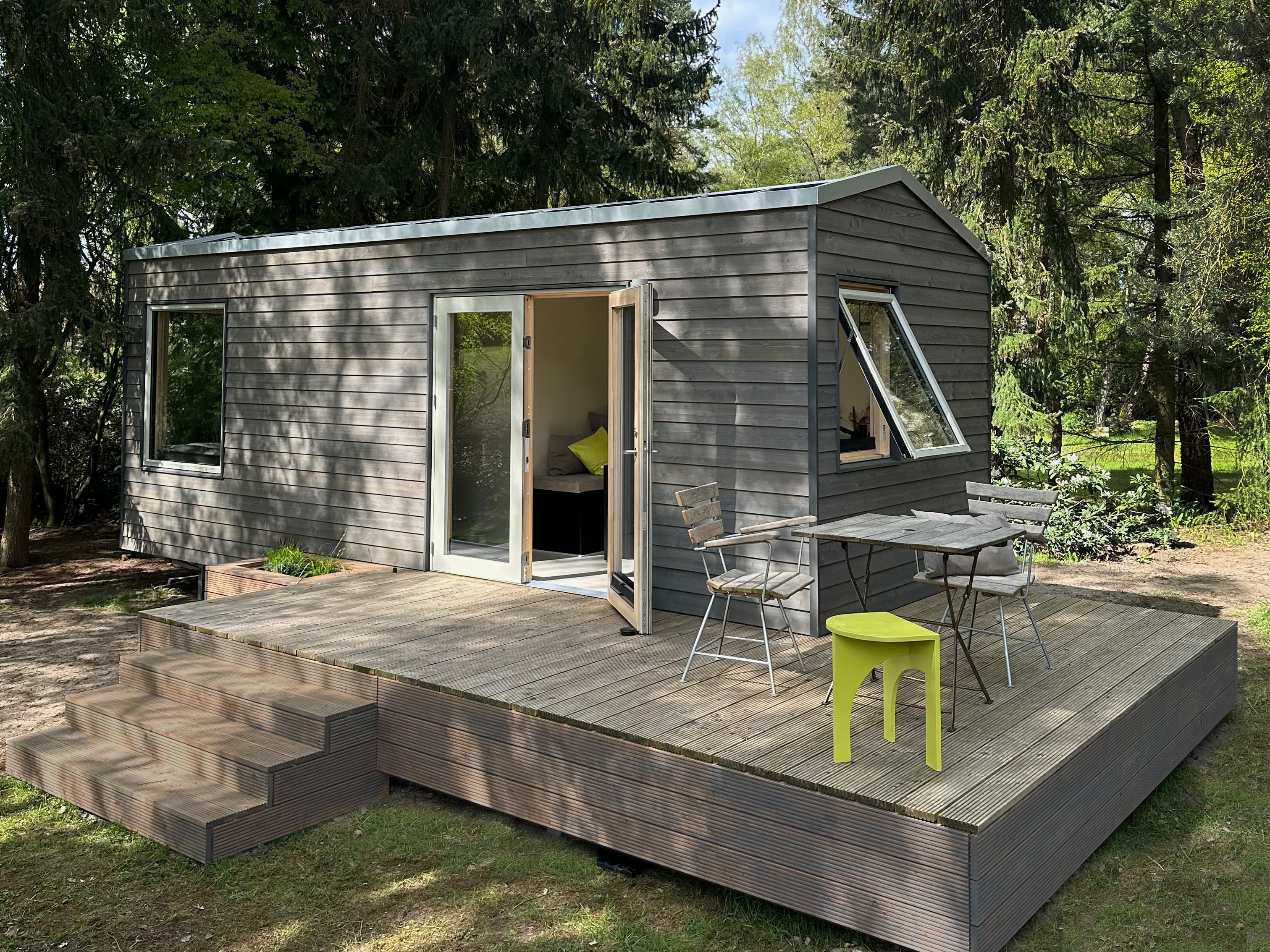 Außenansicht eines Tiny Houses in der Lüneburger Heide mit Bäumen ringsum