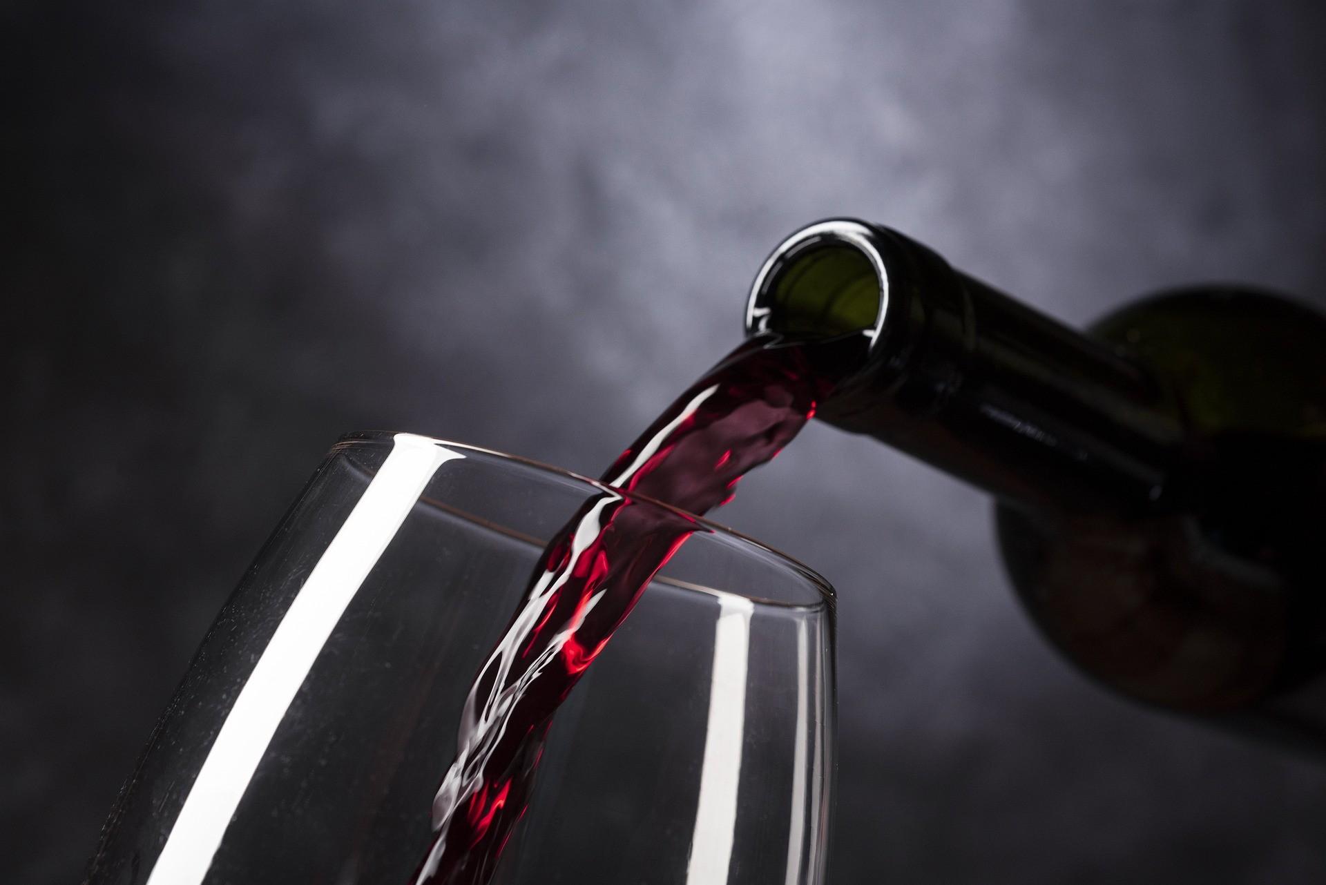 Rotwein fließt aus einer Flasche ins Glas