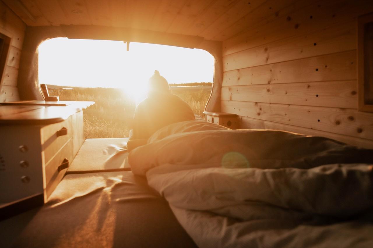 Eine Person sitzt in ihrem Camper, während die Sonne über dem Schwarzwald aufgeht
