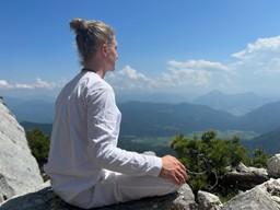 Eine Frau meditiert auf einem Berg.